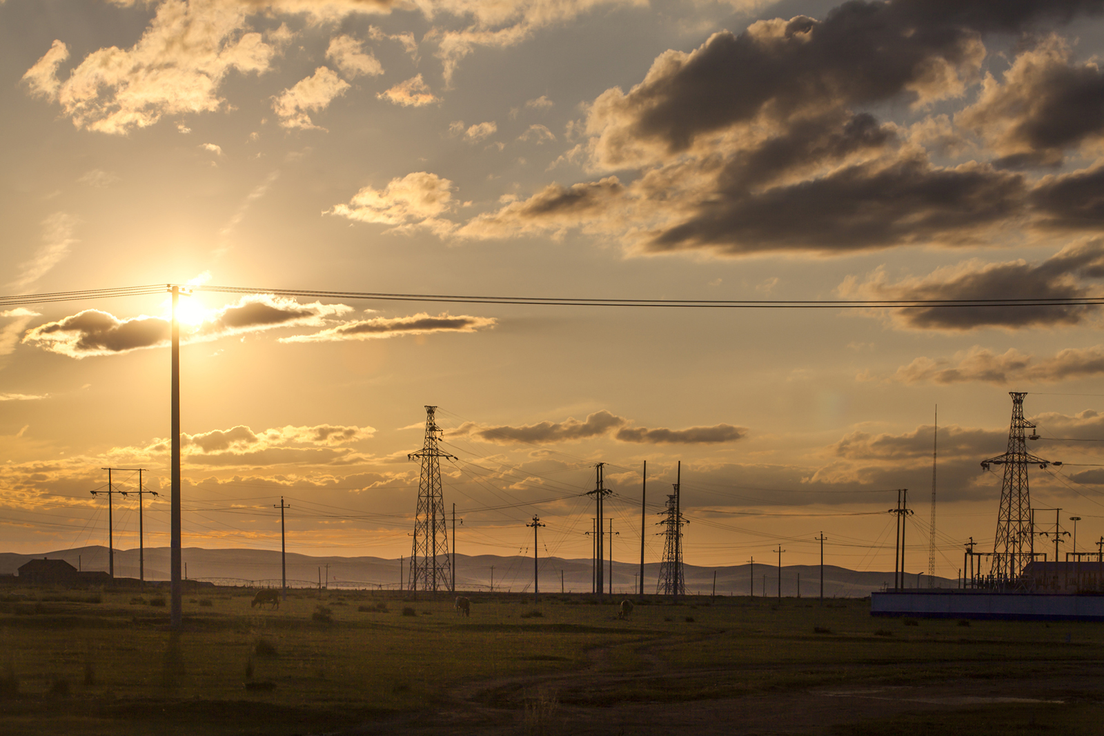 Transmission poles against sunset background